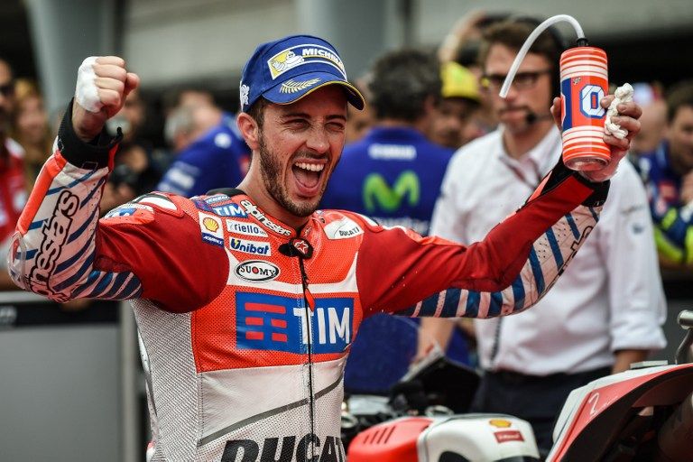 Ducati Team's Italian rider Andrea Dovizioso celebrates at the parc ferme after getting pole position after the qualifying session of Malaysian MotoGP at the Sepang International circuit on October 29, 2016. / AFP PHOTO / MOHD RASFAN